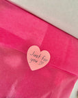 Pink tissue paper with a heart-shaped sticker reading 'Just for you' on a white background