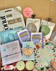 A comforting ‘Thinking of You’ package filled with thoughtful treats and self-care items, such as tea, pamper items, a bracelet, and a handwritten note, neatly arranged in a gift box