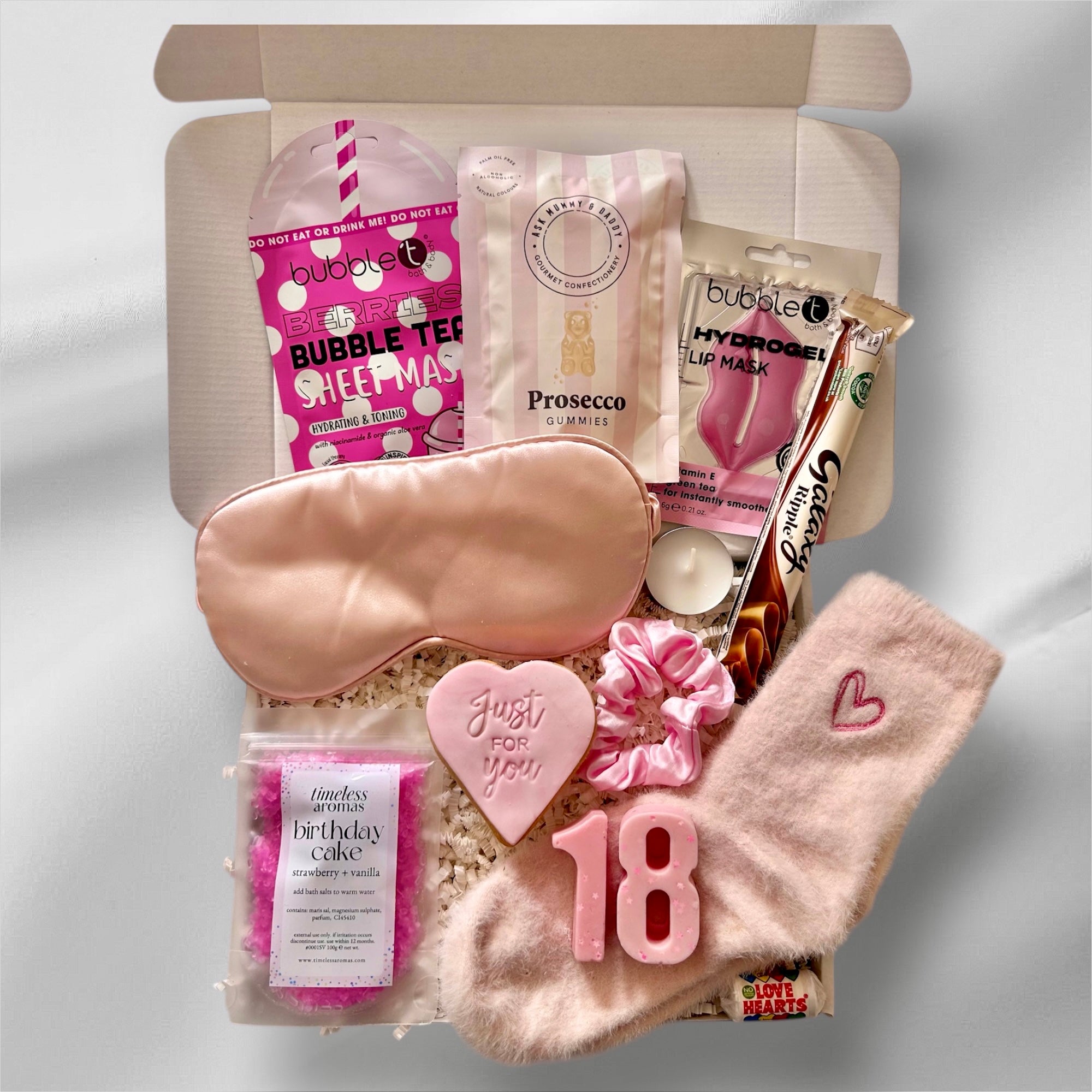 Luxury 18th gift box with soothing face masks, indulgent sweets, premium bath salts, and cozy socks, elegantly packaged for a relaxing and celebratory experience.