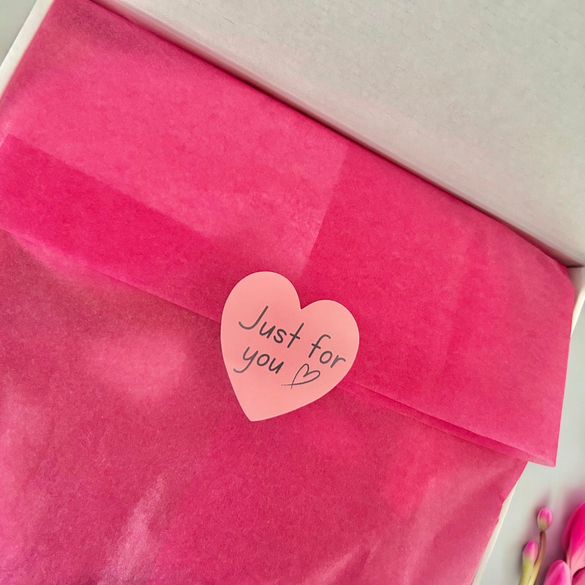 Pink tissue paper with a heart-shaped sticker reading 'Just for you' on a white background