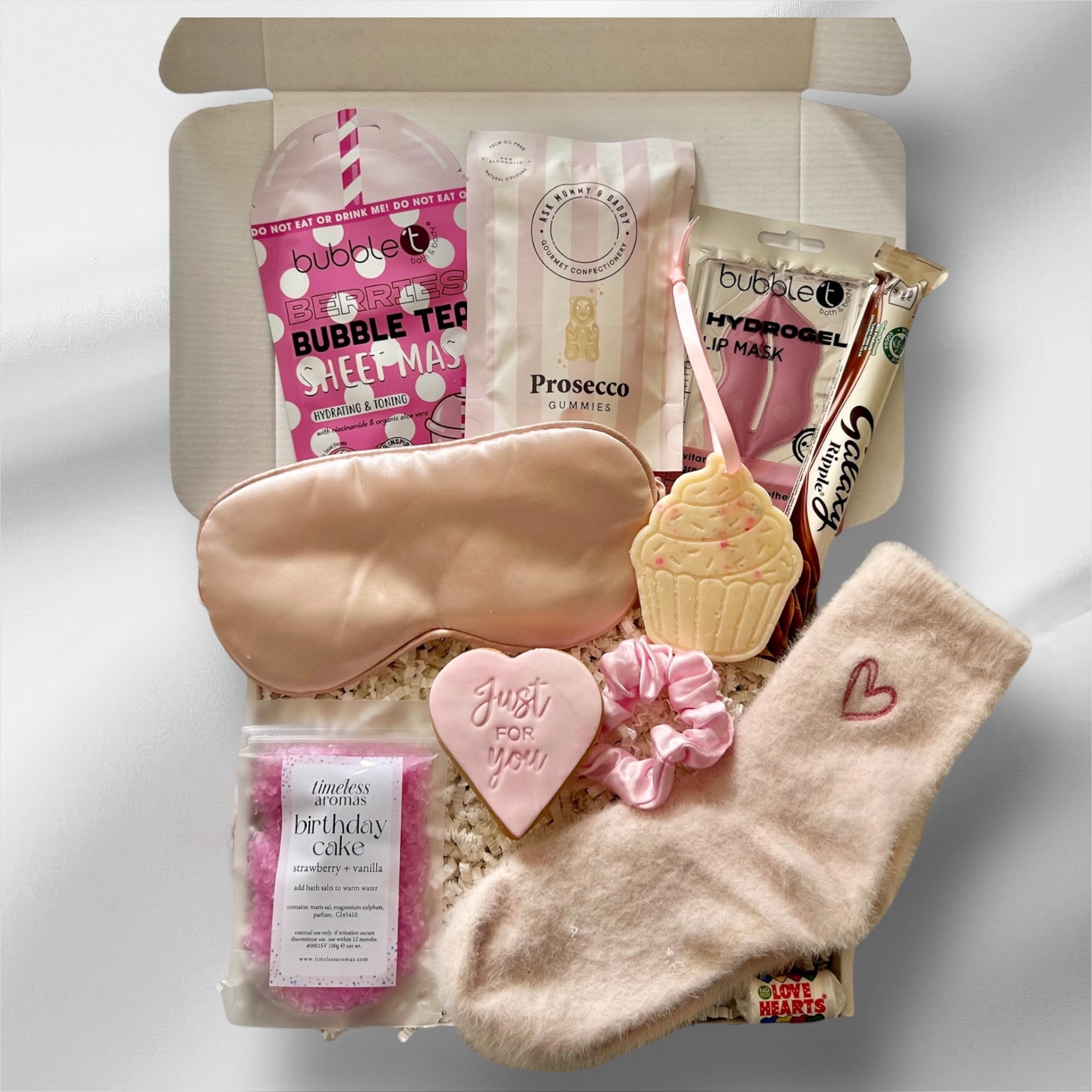 Luxury birthday gift box with soothing face masks, indulgent sweets, premium bath salts, and cozy socks, elegantly packaged for a relaxing and celebratory experience.