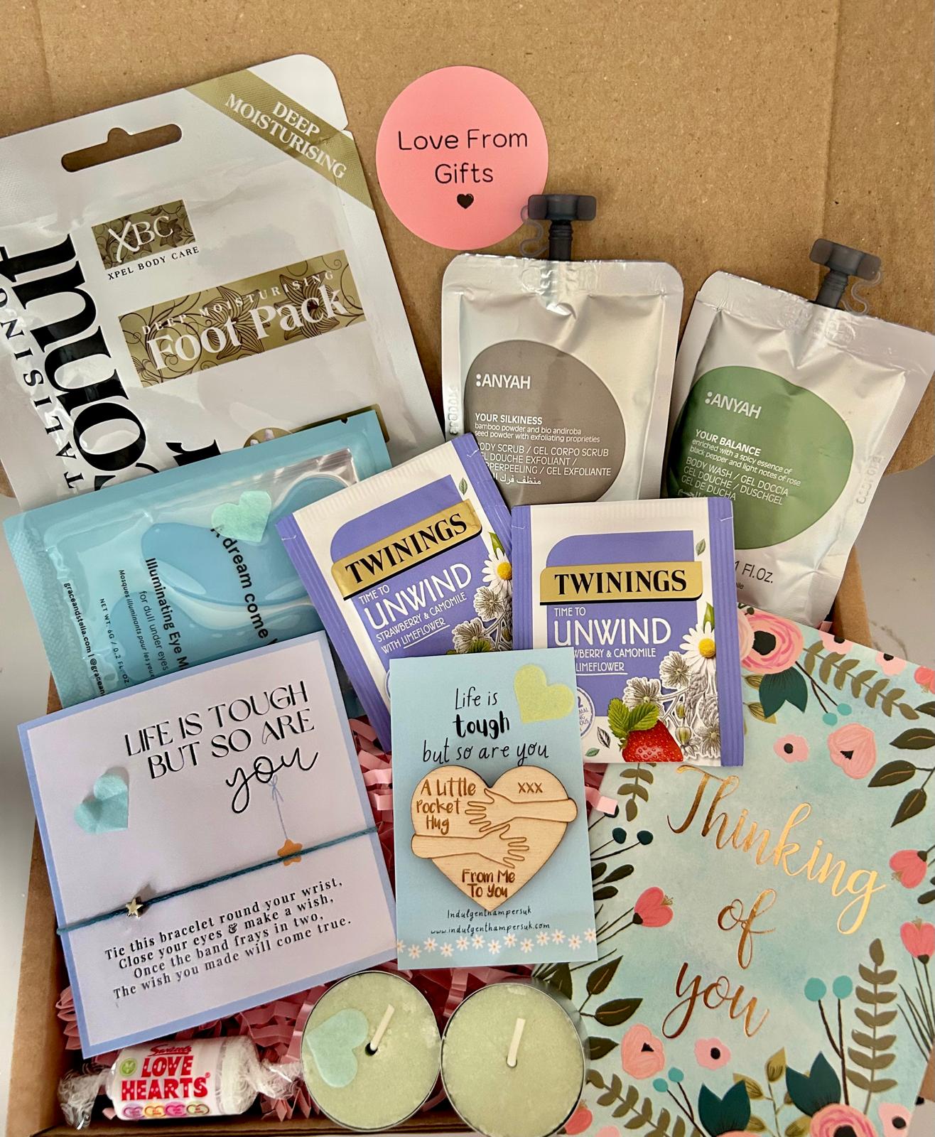 A comforting ‘Thinking of You’ package filled with thoughtful treats and self-care items, such as tea, pamper items, a bracelet, and a handwritten note, neatly arranged in a gift box