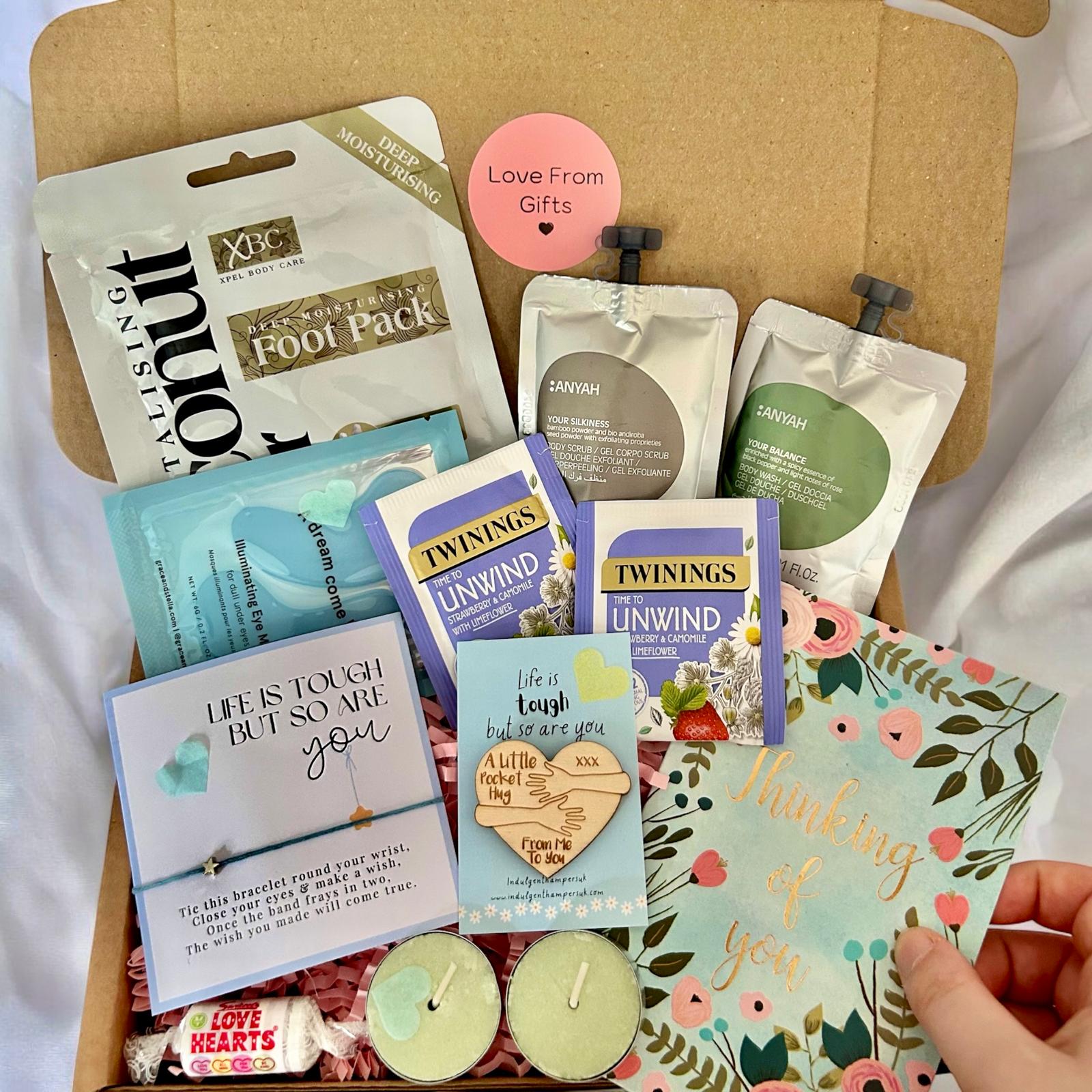 A comforting ‘Thinking of You’ package filled with thoughtful treats and self-care items, such as tea, pamper items, a bracelet, and a handwritten note, neatly arranged in a gift box